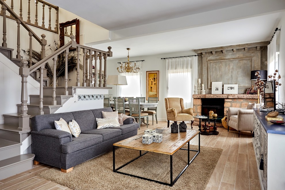 Photo of a large farmhouse open plan living room in Madrid with white walls, a standard fireplace, a stone fireplace surround and beige floors.