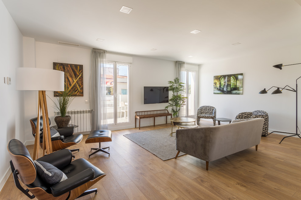 Imagen de salón para visitas abierto minimalista grande sin chimenea con paredes blancas, suelo de madera en tonos medios y televisor colgado en la pared