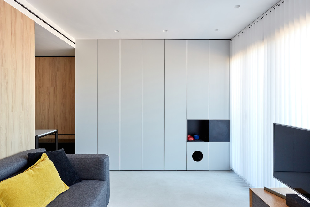 Пример оригинального дизайна: открытая гостиная комната среднего размера в скандинавском стиле с серыми стенами, бетонным полом, отдельно стоящим телевизором и серым полом без камина