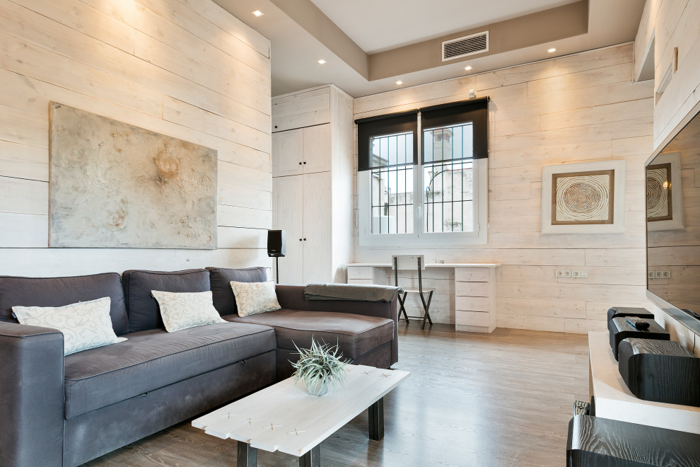 Пример оригинального дизайна: гостиная комната в стиле лофт с бежевыми стенами, паркетным полом среднего тона и телевизором на стене без камина