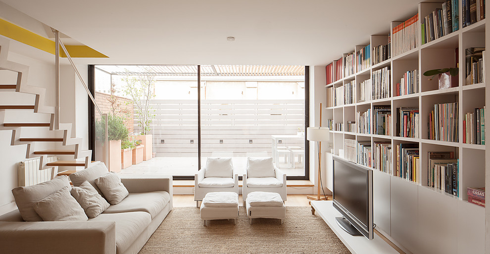 Mittelgroße Skandinavische Bibliothek ohne Kamin, im Loft-Stil mit weißer Wandfarbe, braunem Holzboden und Multimediawand in Barcelona