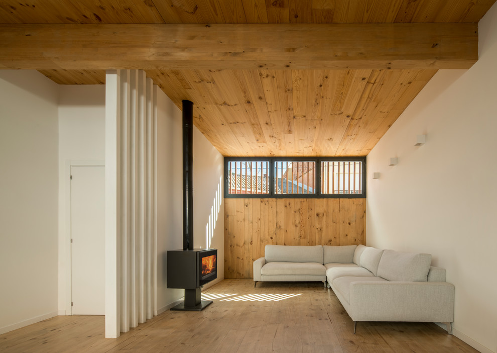 Foto de salón abierto contemporáneo con paredes blancas, suelo de madera en tonos medios, estufa de leña y suelo marrón