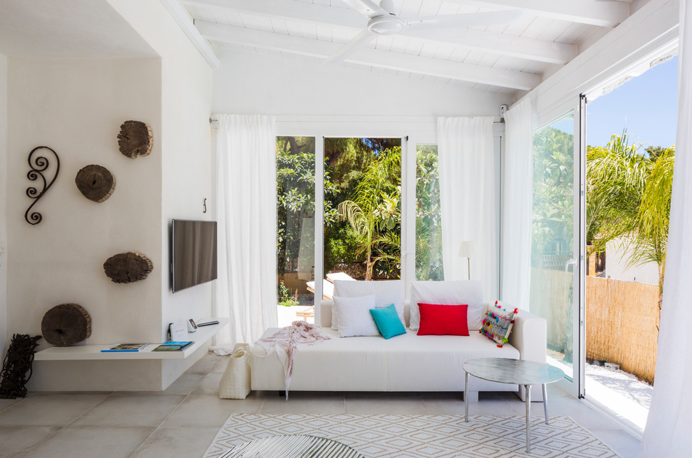 Immagine di un soggiorno mediterraneo di medie dimensioni e aperto con pareti bianche, pavimento con piastrelle in ceramica, TV a parete e pavimento bianco
