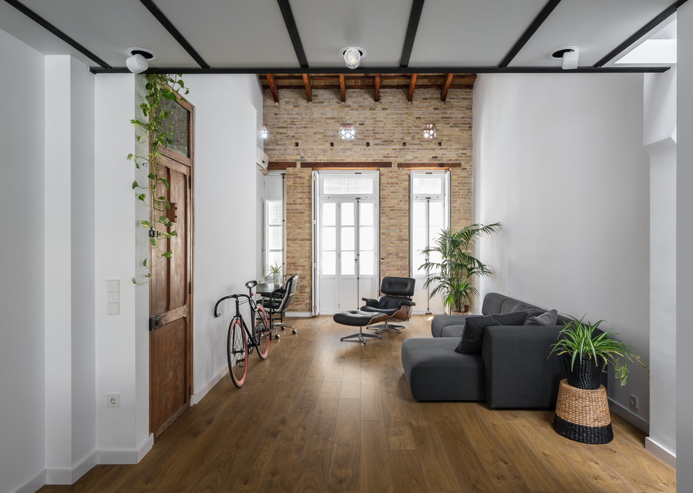 Imagen de salón para visitas abierto urbano de tamaño medio sin chimenea y televisor con paredes blancas y suelo de madera en tonos medios
