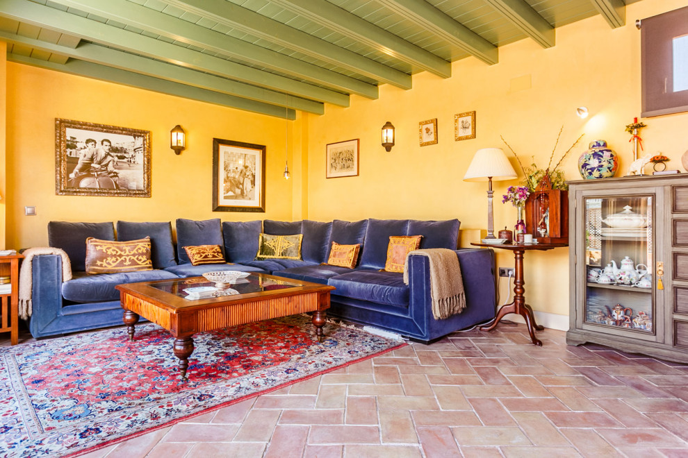 Idee per un soggiorno mediterraneo con pareti gialle, pavimento in terracotta, pavimento rosso e travi a vista