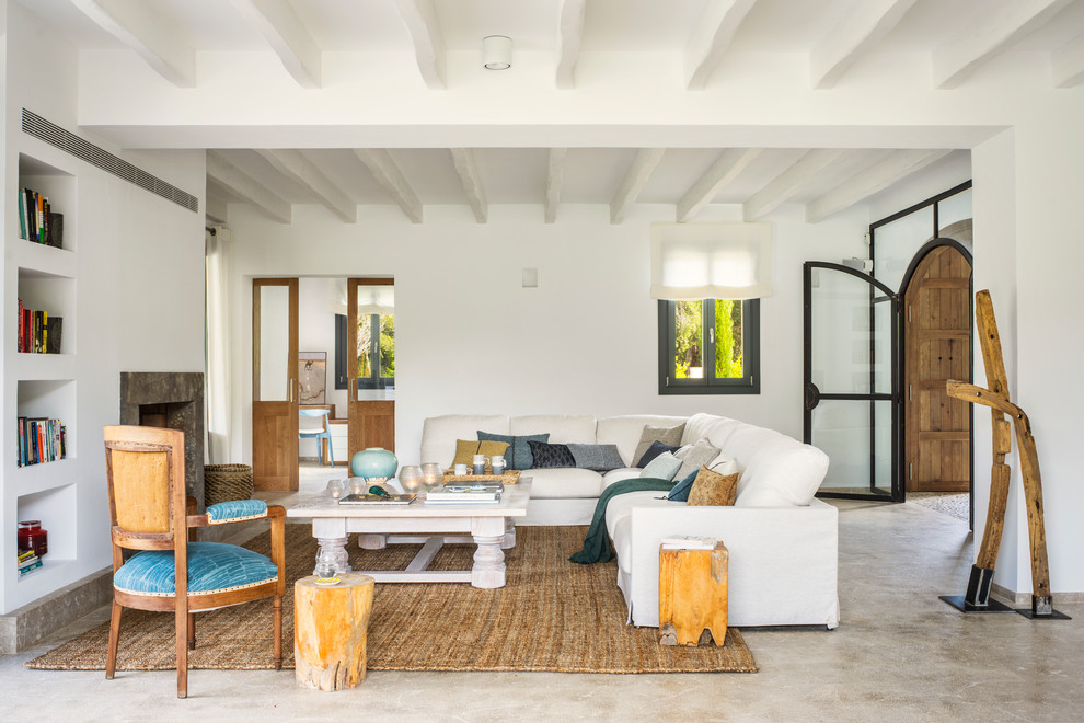 Идея дизайна: гостиная комната в средиземноморском стиле с с книжными шкафами и полками, белыми стенами, стандартным камином, коричневым полом и ковром на полу без телевизора