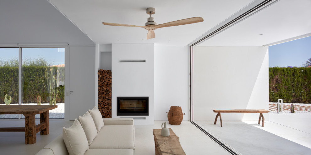 Cette photo montre un salon moderne ouvert avec un mur blanc, sol en béton ciré, une cheminée standard et un sol blanc.