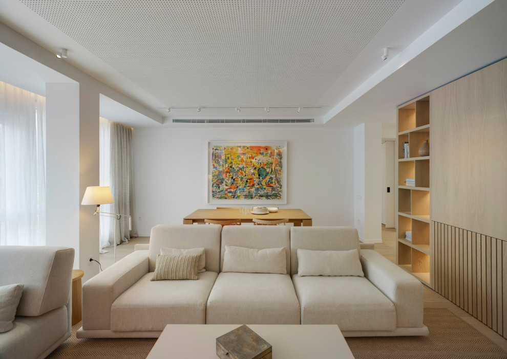 Aménagement d'un salon contemporain avec une bibliothèque ou un coin lecture, un mur blanc, parquet clair et un téléviseur fixé au mur.