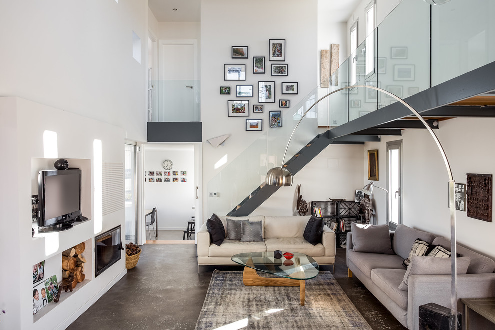 Cette photo montre un salon tendance ouvert avec un mur blanc, un sol gris, une cheminée standard, un téléviseur fixé au mur et un escalier.