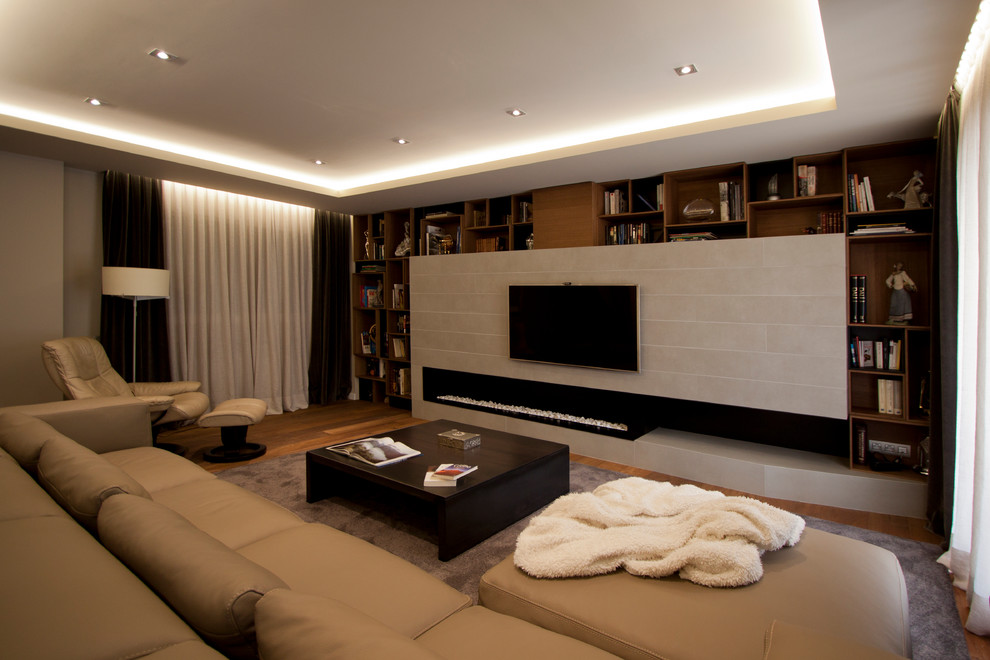 Ejemplo de salón abierto actual grande sin chimenea con paredes beige, suelo de madera en tonos medios y televisor colgado en la pared