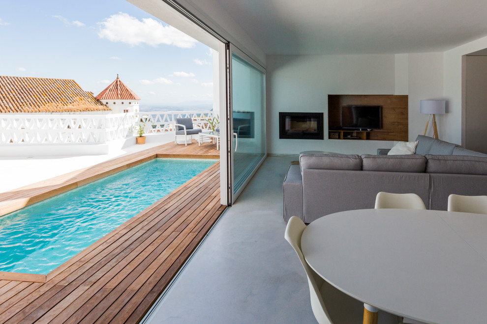 Immagine di un soggiorno mediterraneo di medie dimensioni e aperto con sala formale, pareti bianche, pavimento in cemento, stufa a legna e parete attrezzata