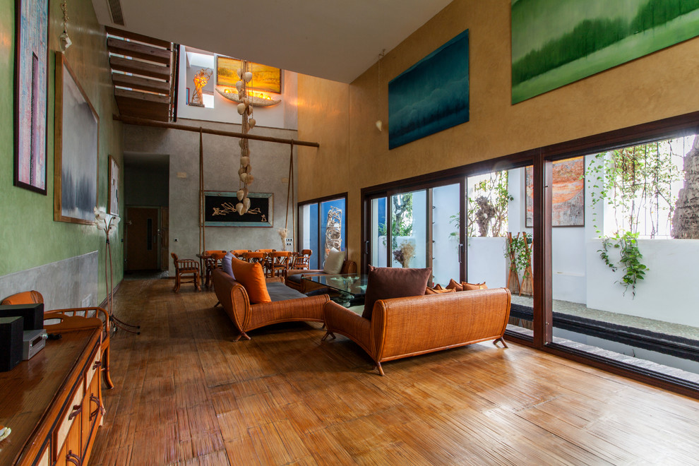Imagen de salón para visitas abierto tropical grande sin chimenea y televisor con paredes multicolor y suelo de madera en tonos medios