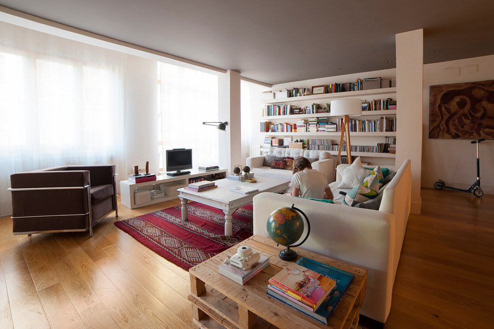 Imagen de biblioteca en casa abierta escandinava grande sin chimenea con paredes blancas, suelo de madera en tonos medios y televisor independiente