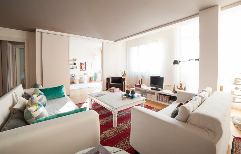 Exemple d'un grand salon scandinave ouvert avec une bibliothèque ou un coin lecture, un mur blanc, un sol en bois brun et un téléviseur encastré.