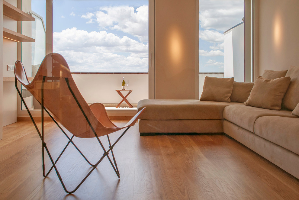 Foto de salón para visitas abierto minimalista de tamaño medio sin chimenea con paredes beige, televisor colgado en la pared y suelo de madera en tonos medios