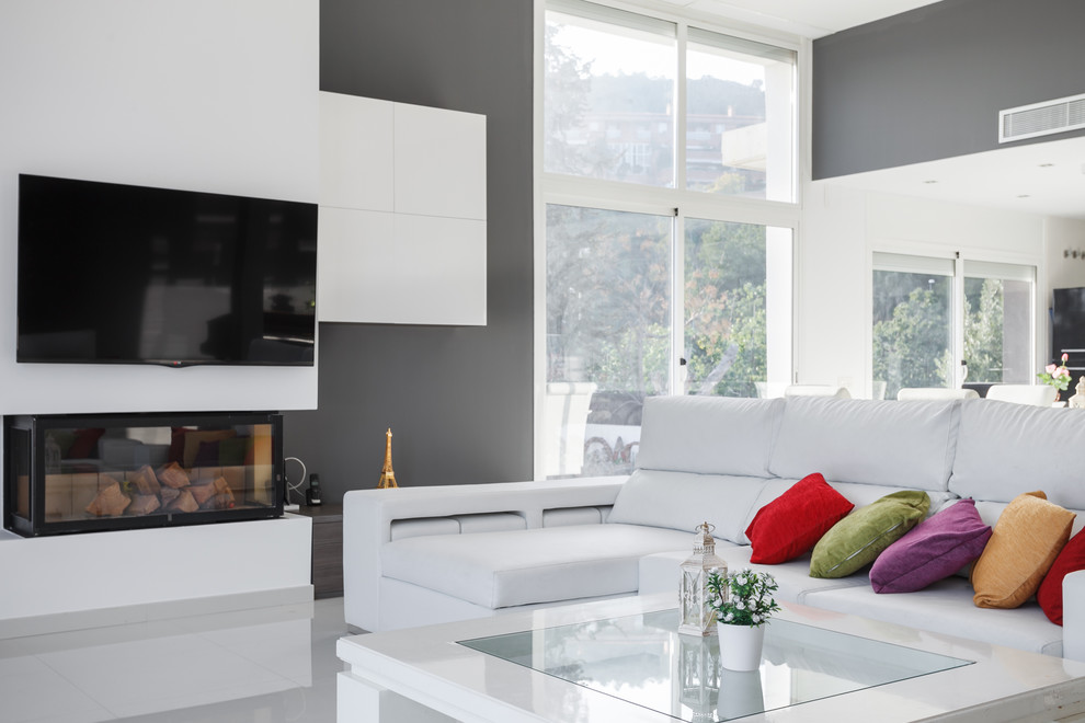 Foto di un ampio soggiorno moderno aperto con pareti grigie, camino lineare Ribbon, cornice del camino in metallo, TV a parete e pavimento bianco