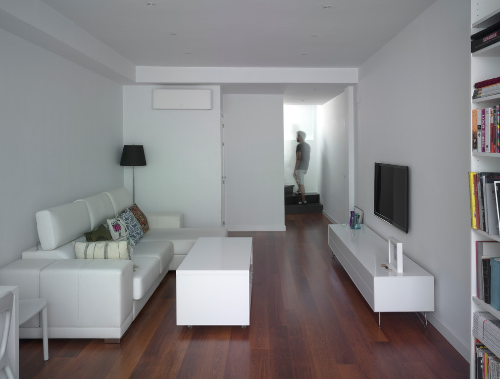 Cette image montre un petit salon minimaliste ouvert avec un mur blanc, parquet foncé et un téléviseur fixé au mur.