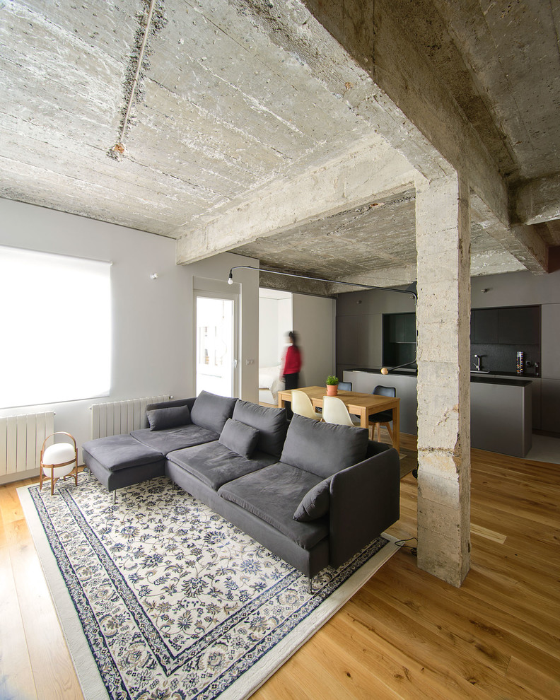 Immagine di un soggiorno industriale aperto con pavimento in legno massello medio, pareti bianche e pavimento marrone