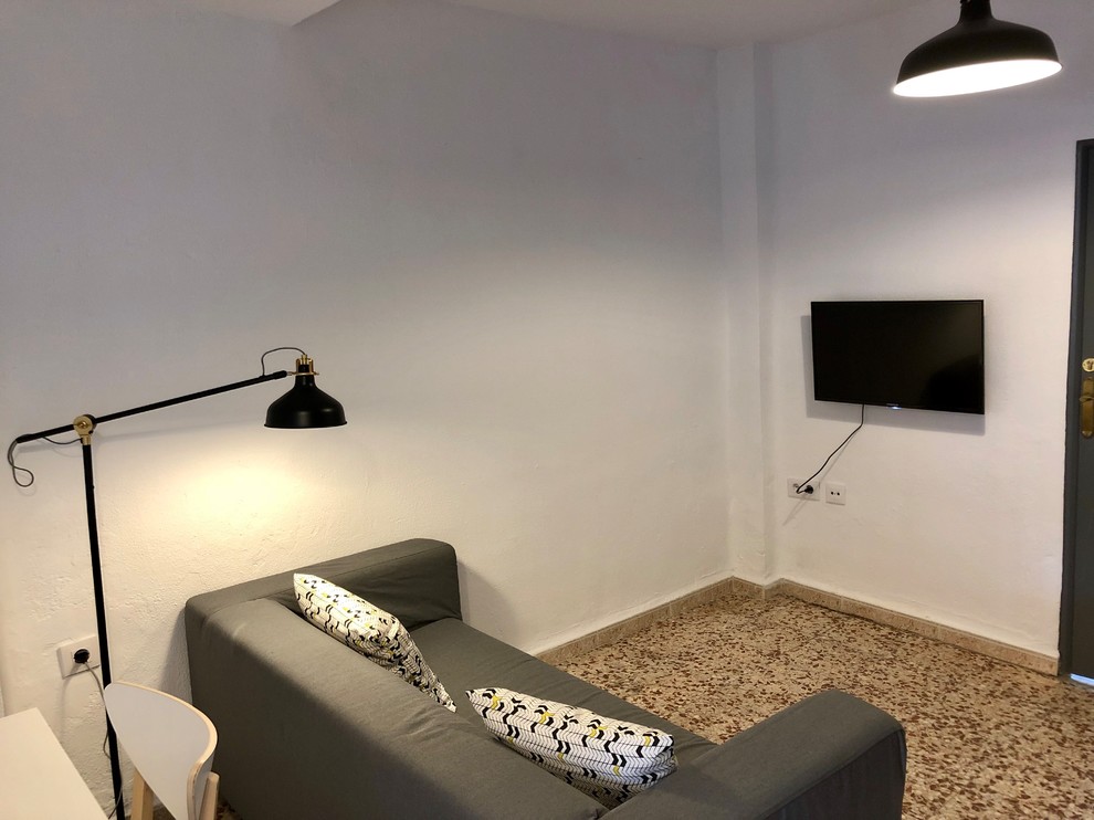 Modelo de salón abierto tradicional renovado pequeño sin chimenea con paredes blancas, televisor colgado en la pared y suelo multicolor