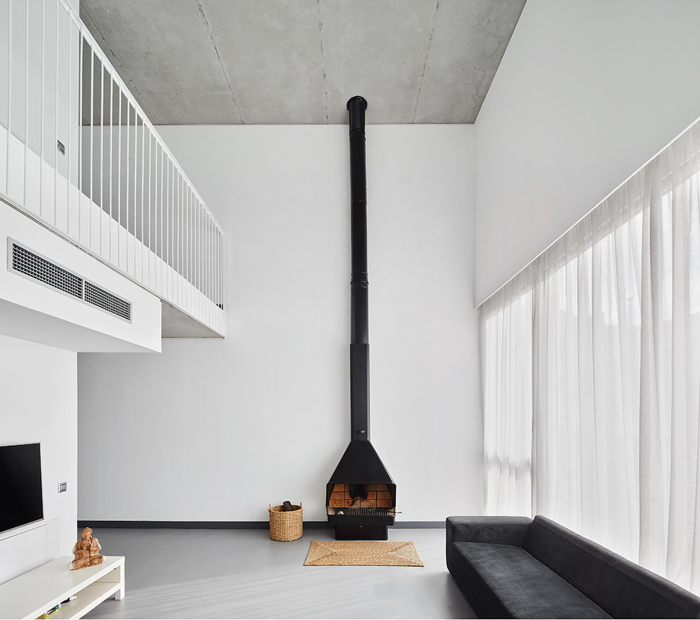 Ispirazione per un soggiorno design di medie dimensioni con pareti bianche, pavimento in cemento, stufa a legna, cornice del camino in metallo e TV a parete