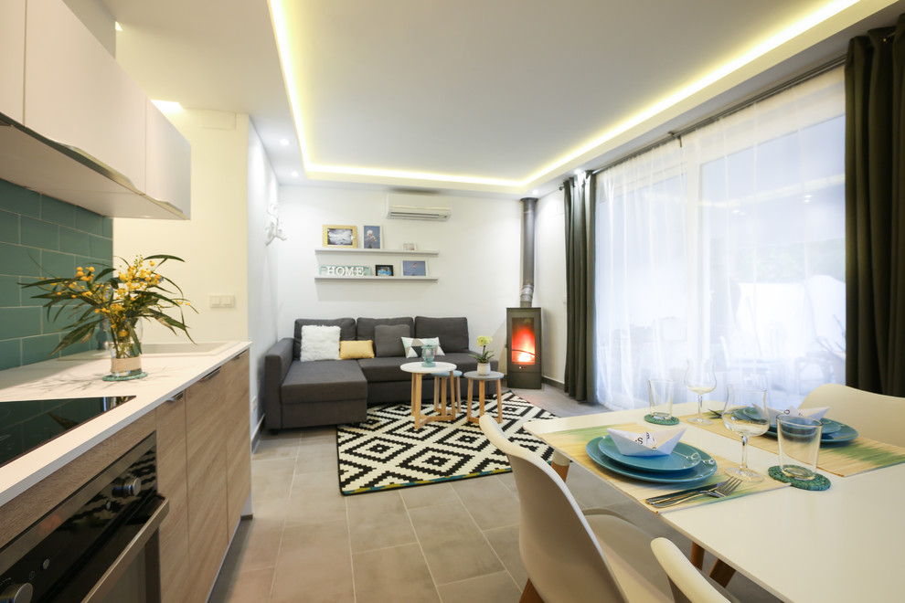 Mittelgroßes, Fernseherloses, Offenes Mediterranes Wohnzimmer mit weißer Wandfarbe, Porzellan-Bodenfliesen und Kaminofen in Malaga