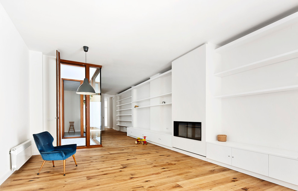 Foto de salón abierto contemporáneo sin televisor con paredes blancas, suelo de madera en tonos medios, chimenea lineal, marco de chimenea de metal y suelo marrón