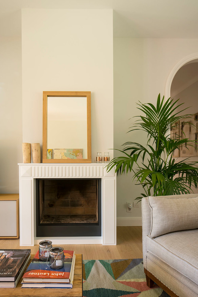 Exemple d'un grand salon scandinave fermé avec un mur blanc, un sol en bois brun, un téléviseur indépendant, un sol marron, une cheminée standard et un manteau de cheminée en plâtre.