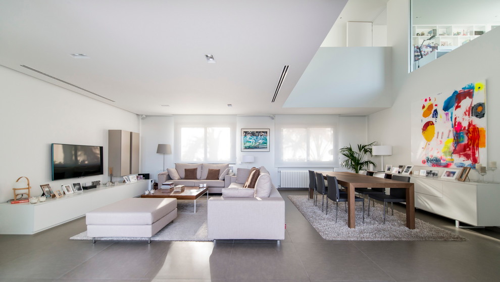 Modelo de salón abierto minimalista grande sin chimenea con paredes blancas, televisor colgado en la pared y suelo de baldosas de cerámica