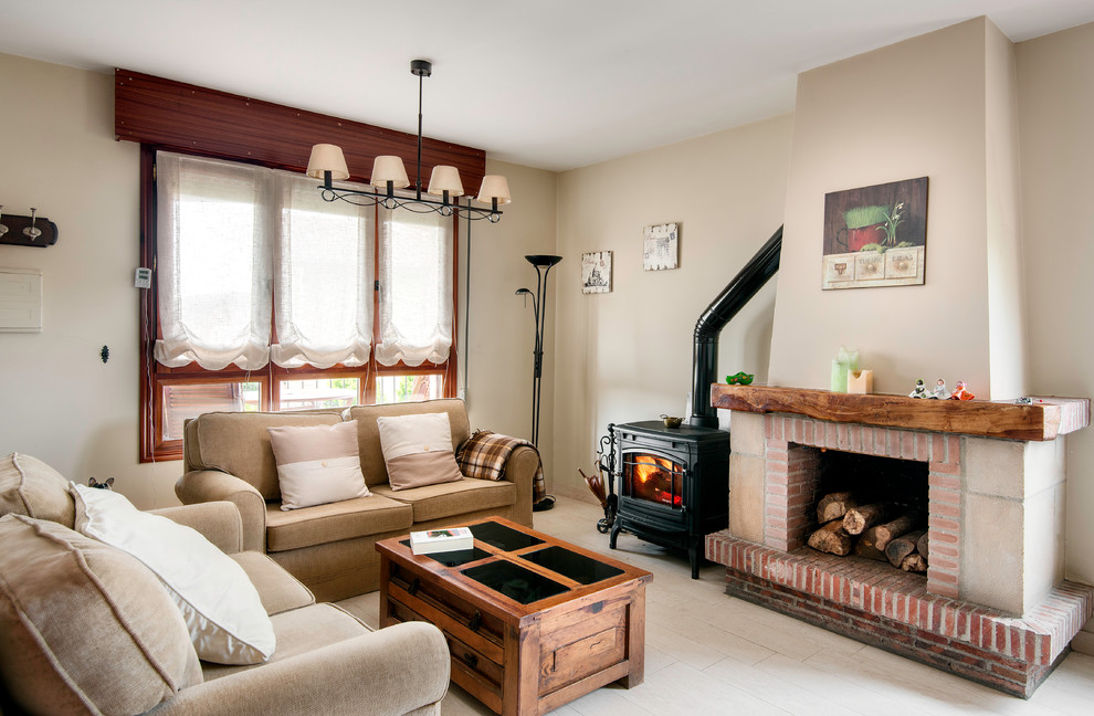 This is an example of a medium sized country open plan living room in Bilbao with beige walls, painted wood flooring, a standard fireplace, a brick fireplace surround and no tv.