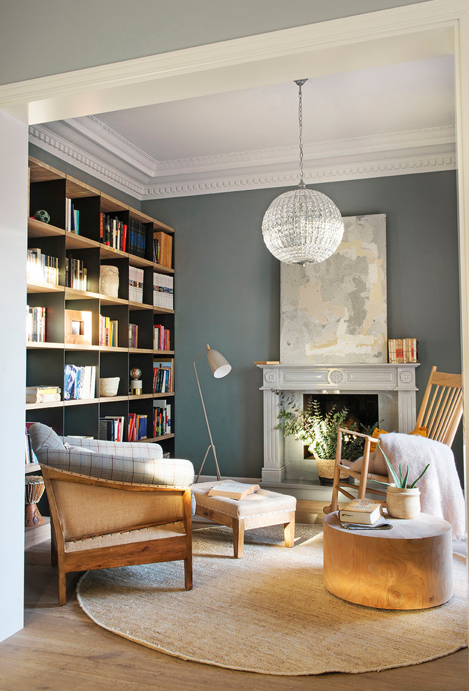 Exempel på ett mellanstort klassiskt allrum med öppen planlösning, med ett bibliotek, grå väggar, ljust trägolv, brunt golv och en standard öppen spis