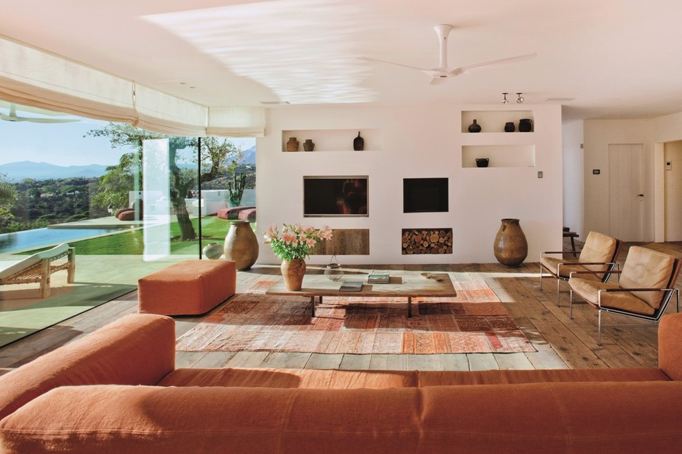 Medium sized mediterranean formal open plan living room in Barcelona with white walls, medium hardwood flooring, a standard fireplace and a wall mounted tv.