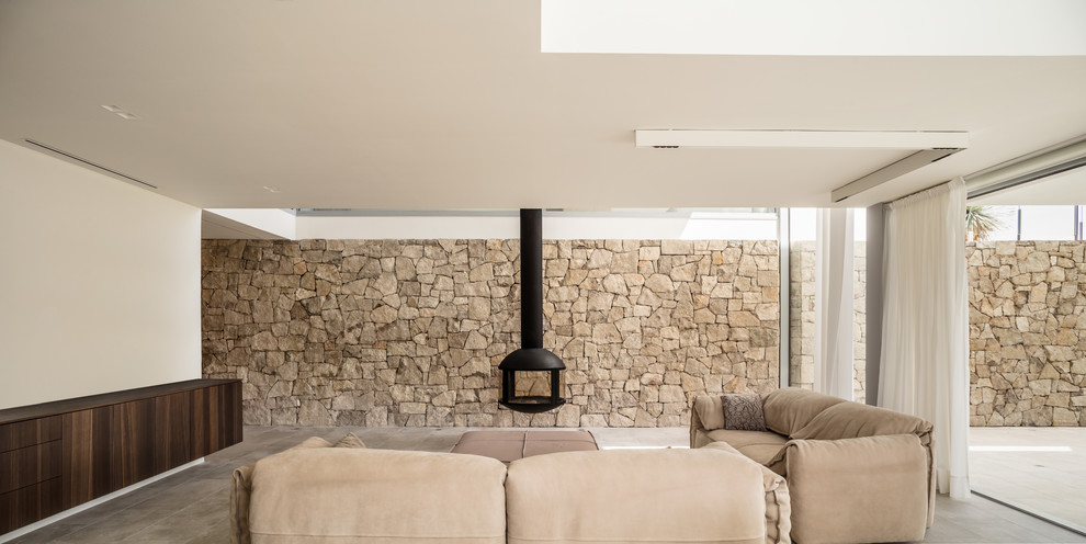 Cette photo montre un salon moderne avec un mur beige, cheminée suspendue, un sol gris et un mur en pierre.