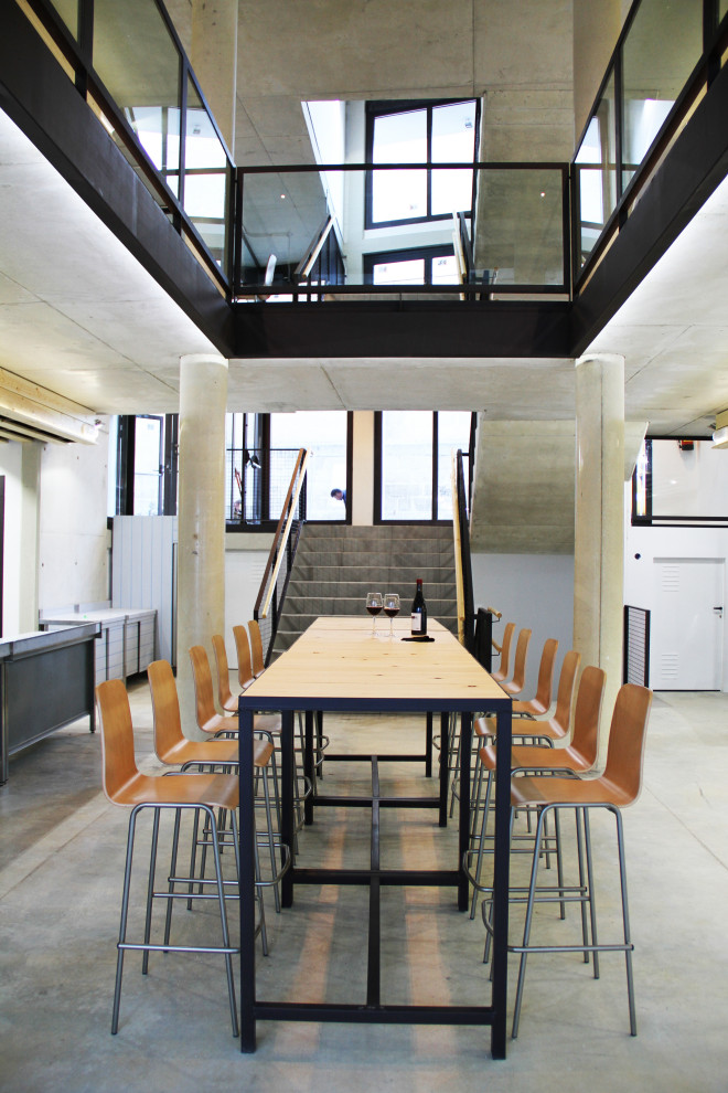 Ispirazione per una sala da pranzo industriale di medie dimensioni con pareti bianche, pavimento in cemento, pavimento grigio e pareti in mattoni