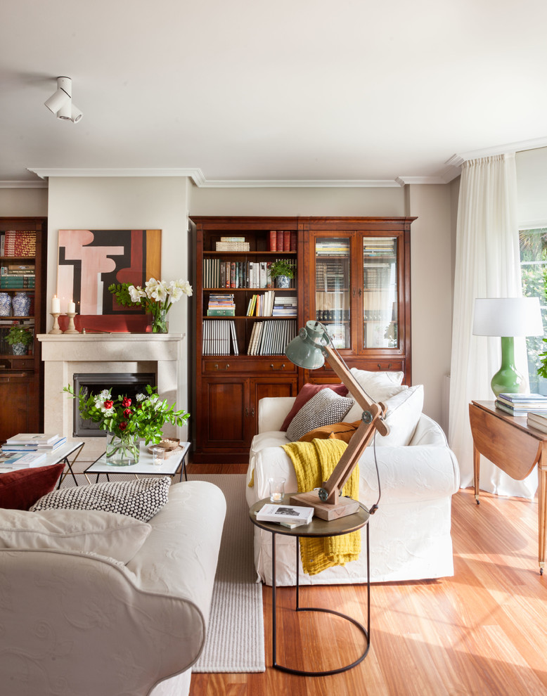 Esempio di un soggiorno tradizionale con sala formale, pareti grigie, pavimento in legno massello medio, camino classico e pavimento marrone