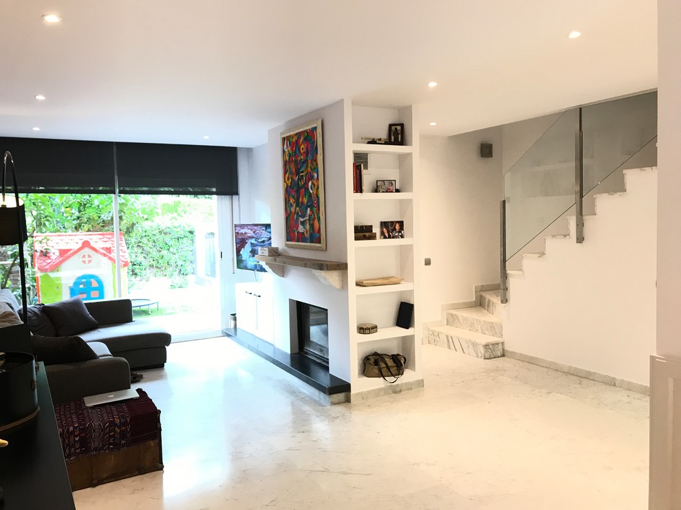 バルセロナにある高級な広いエクレクティックスタイルのおしゃれなLDK (ライブラリー、白い壁、大理石の床、横長型暖炉、漆喰の暖炉まわり、壁掛け型テレビ、白い床) の写真