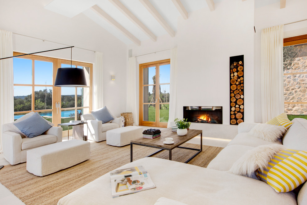 Источник вдохновения для домашнего уюта: открытая гостиная комната в средиземноморском стиле с белыми стенами, стандартным камином, фасадом камина из камня и белым полом без телевизора