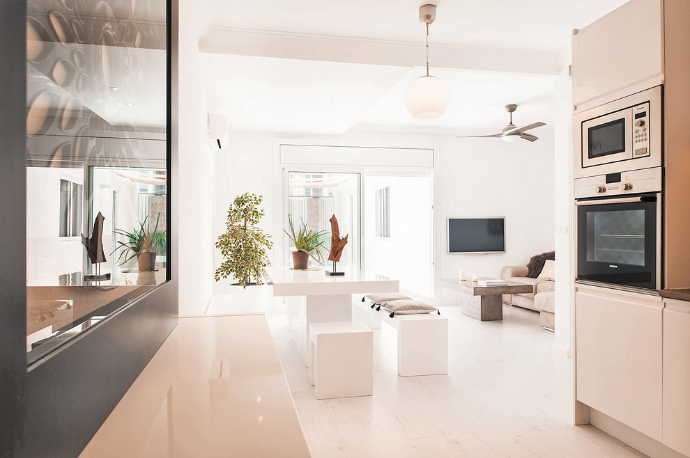 Modelo de salón abierto contemporáneo de tamaño medio con paredes blancas, suelo de madera clara y televisor colgado en la pared