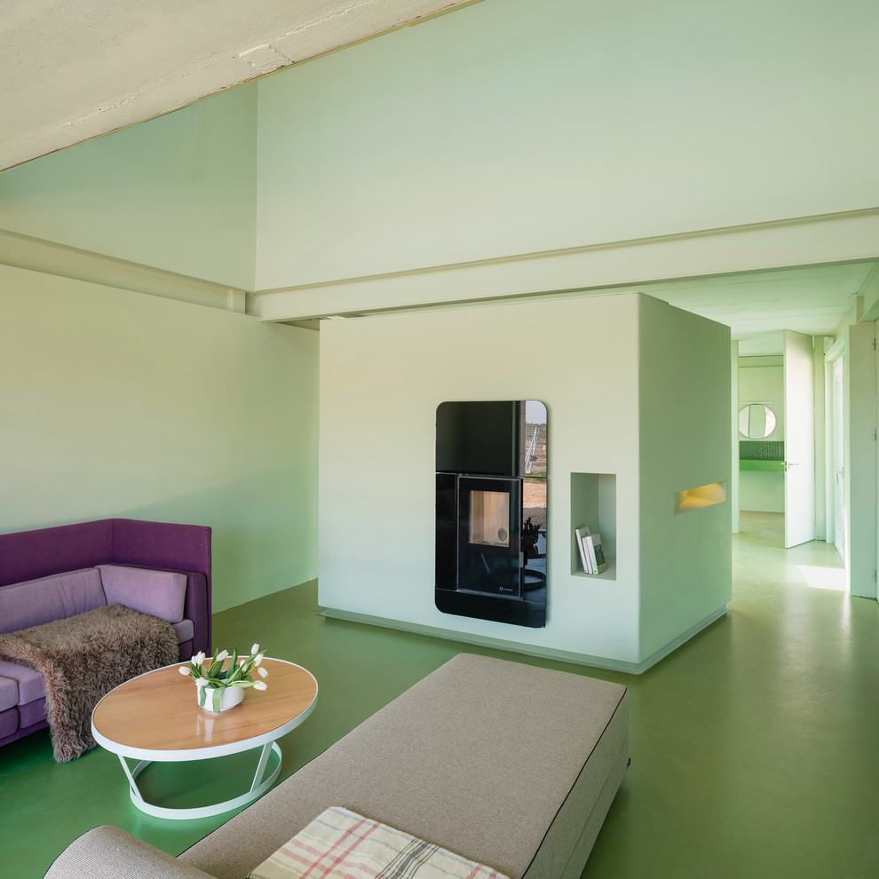 Стильный дизайн: гостиная комната в современном стиле с зелеными стенами, бетонным полом и фасадом камина из штукатурки - последний тренд