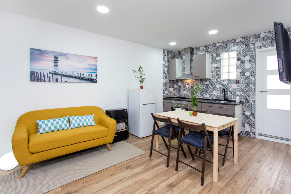 На фото: маленькая открытая гостиная комната в современном стиле с белыми стенами, паркетным полом среднего тона, телевизором на стене и коричневым полом для на участке и в саду с