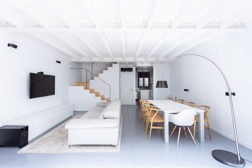 Imagen de salón abierto contemporáneo sin chimenea con paredes blancas, televisor colgado en la pared y suelo gris