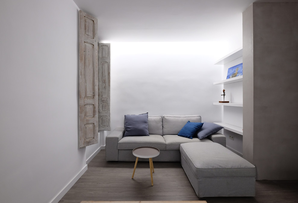 Стильный дизайн: открытая гостиная комната среднего размера в стиле лофт с с книжными шкафами и полками, белыми стенами, полом из ламината и коричневым полом - последний тренд