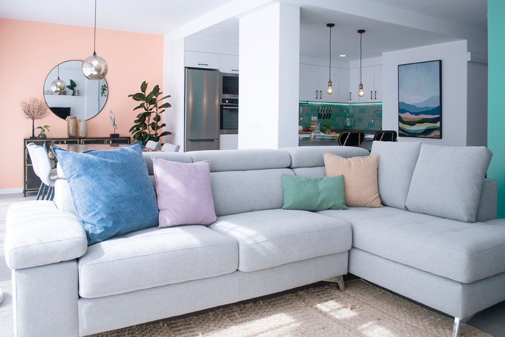 Imagen de salón abierto bohemio de tamaño medio con suelo de cemento, televisor colgado en la pared, suelo gris y paredes rosas