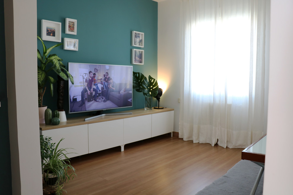 Cette image montre un petit salon minimaliste ouvert avec un mur vert, sol en stratifié, aucune cheminée, un téléviseur indépendant et un sol marron.