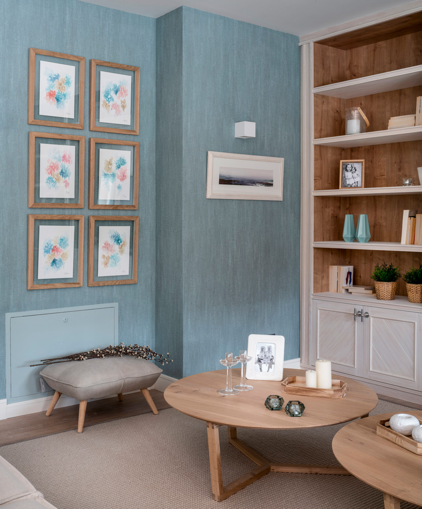 Idée de décoration pour un grand salon nordique ouvert avec une bibliothèque ou un coin lecture, un mur bleu, sol en stratifié, aucune cheminée, un téléviseur encastré et un sol marron.