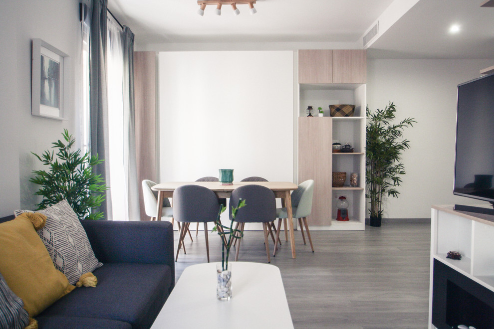 Modern inredning av ett litet loftrum, med ett finrum, vita väggar, mellanmörkt trägolv, en bred öppen spis, en spiselkrans i metall, en inbyggd mediavägg och grått golv