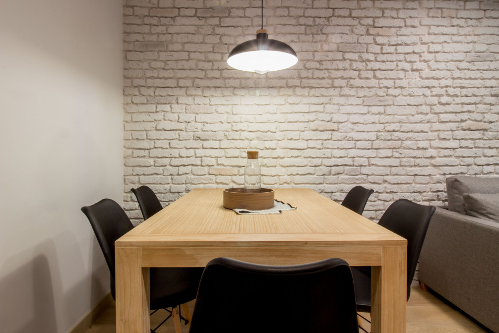 Foto de comedor pequeño con paredes grises, suelo de madera clara y ladrillo