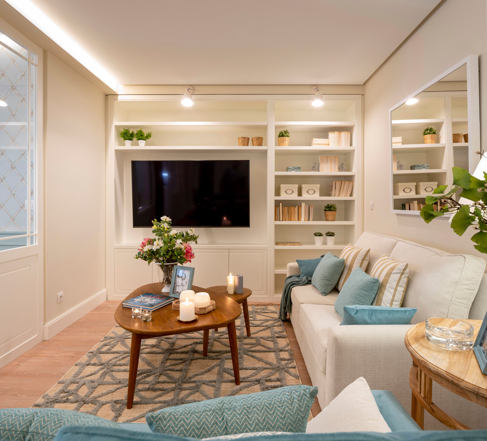 Esempio di un soggiorno chic di medie dimensioni e aperto con libreria, pareti beige, pavimento in laminato, nessun camino, TV a parete e pavimento marrone