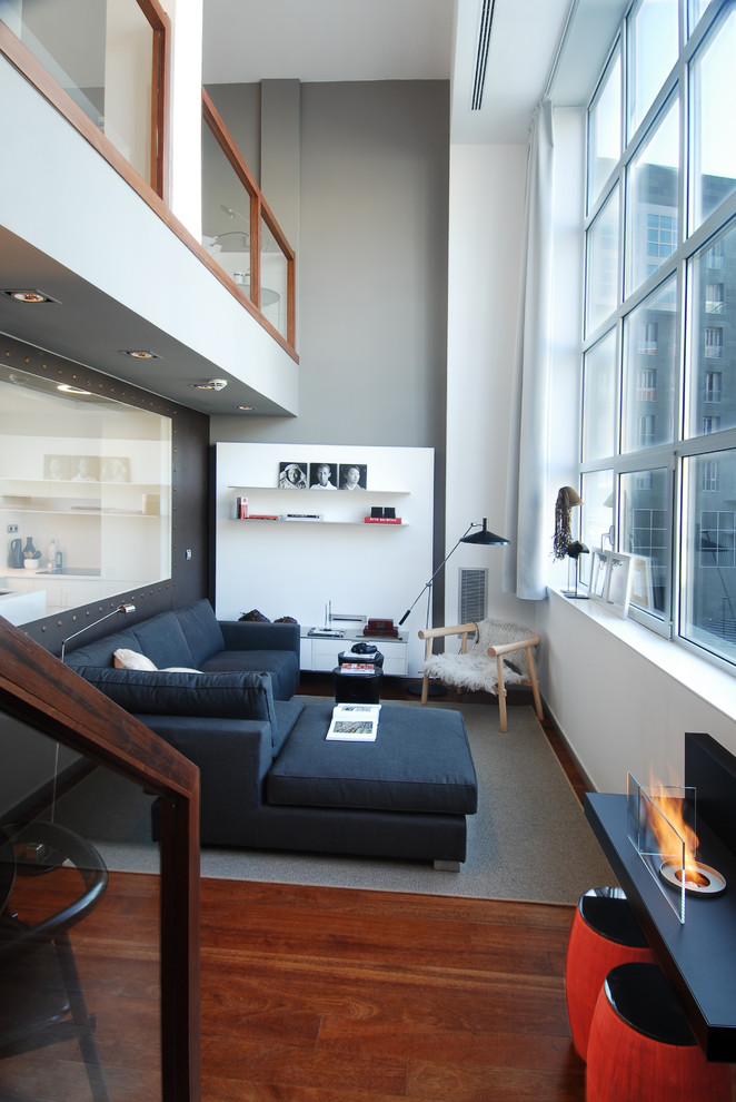 На фото: двухуровневая гостиная комната среднего размера в современном стиле с белыми стенами и темным паркетным полом без телевизора
