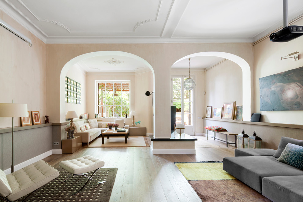 Modelo de salón abierto grande con paredes beige, suelo de madera clara y suelo beige