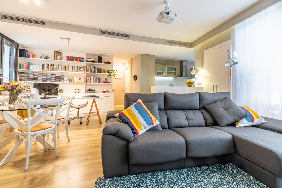 Immagine di un soggiorno design di medie dimensioni e stile loft con libreria, pareti beige, pavimento in laminato, TV nascosta e pavimento marrone